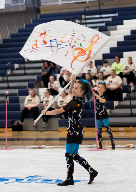 A young child spinning a flag for a winter guard performance.