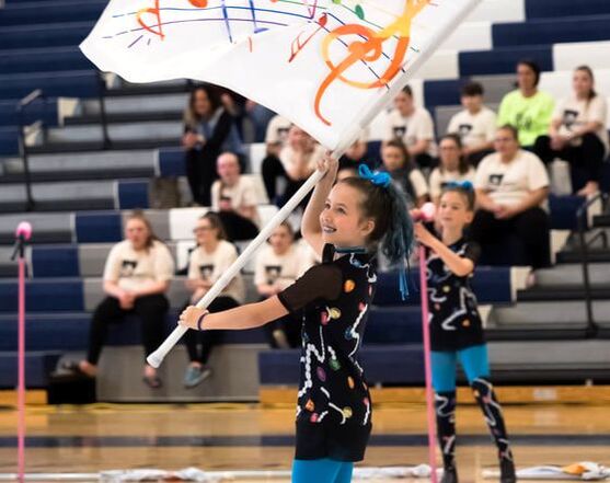 A young child spins a flag for a winter guard performance.