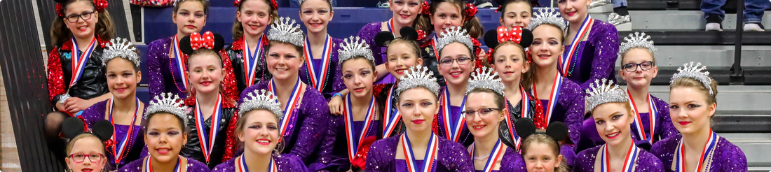 A group of ventures winter guard participants wearing medals and holding trophies.Picture